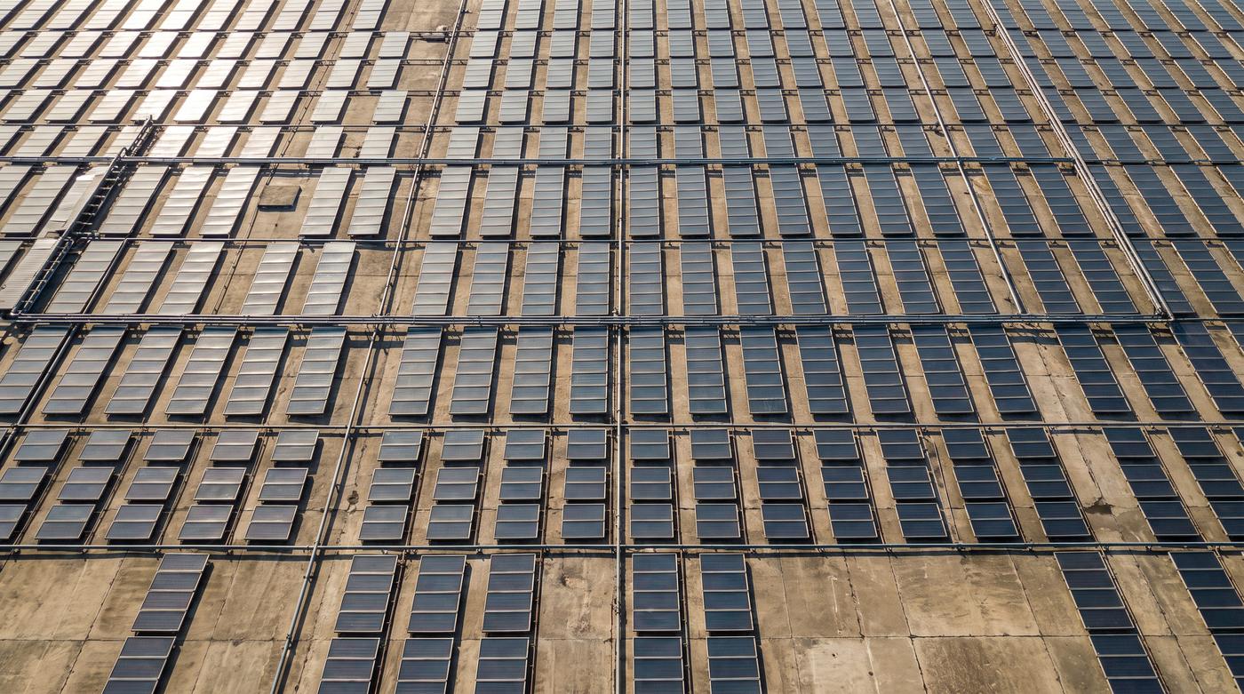 Vista aérea de cima de um campo extenso de coletores solares planos em fileiras paralelas