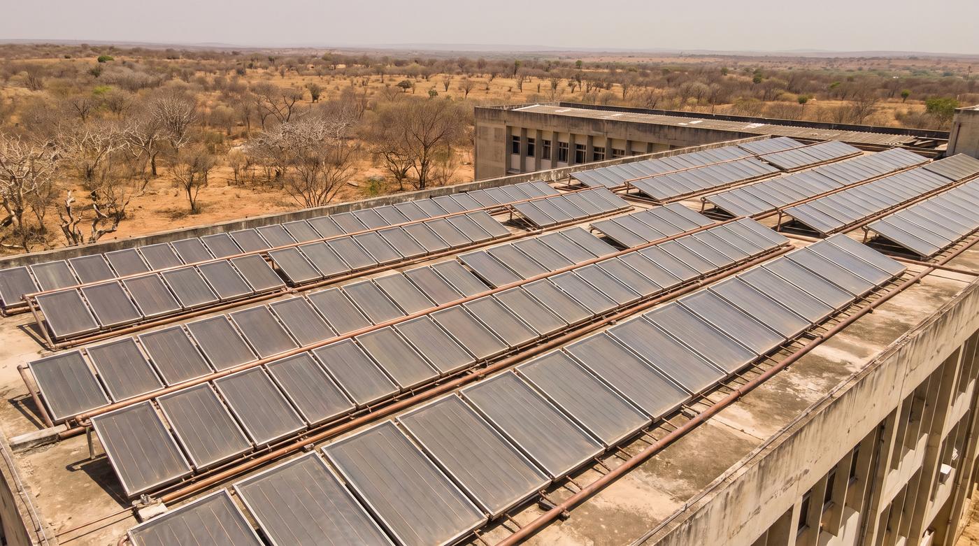 Campo de coletores solares planos em cobertura no semiárido brasileiro, sob sol de meio-dia